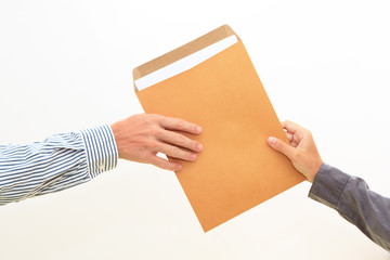 woman's hand passes envelope to male hand on white background