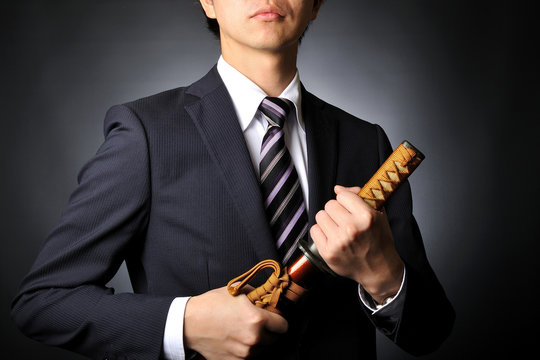 侍の刀を持っているスーツのビジネスマン