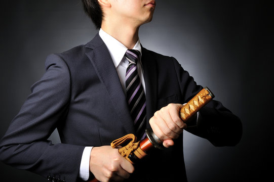 侍の刀を持っているスーツのビジネスマン
