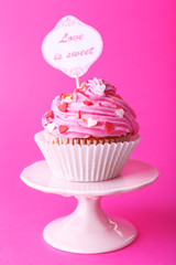 Delicious cupcake with inscription on pink background