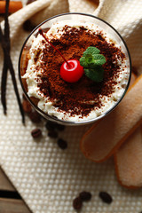 Tasty tiramisu dessert in glass, on napkin, on wooden