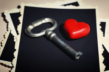 Retro key with photos and heart on wooden table background