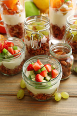 Healthy layered desserts with muesli and fruits on table