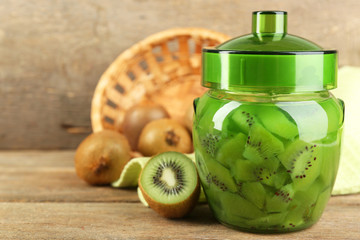 Tasty kiwi jam in glass jar on wooden background