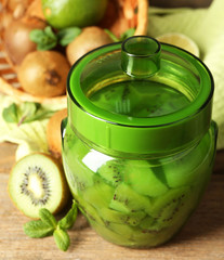 Tasty kiwi jam in glass jar on wooden background