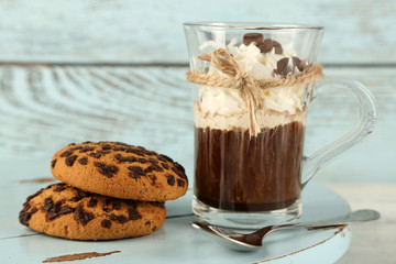 Cup of coffee with cream and cookies on wooden background