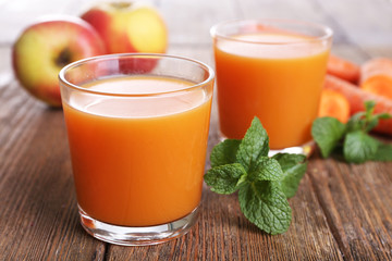 Glasses of juice with apple and carrot on wooden table close up