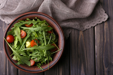Salad with arugula and cherry tomatoes on wooden table