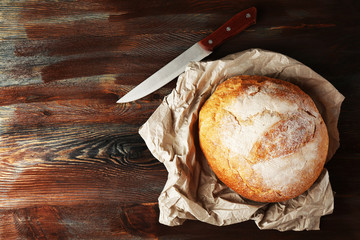 Fresh bread on paper on wooden background