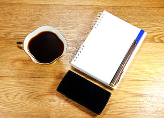 cup of coffee, a phone and a notepad