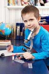 Boy with microscope at home