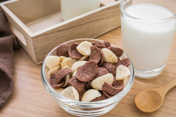 Chocolate and white chocolate cereals in bowl with milk glass