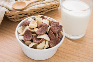 Chocolate and white chocolate cereals in bowl with milk glass