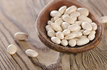 Fototapeta na wymiar White beans in a old wooden spoon.