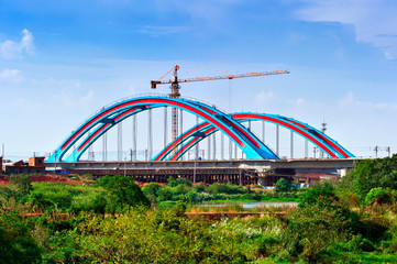 Fototapeta na wymiar Construction of a new bridge with a high construction crane