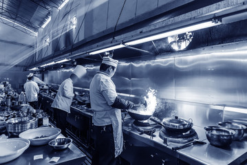 Crowded kitchen, a narrow aisle, working chef.