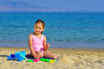 Toddler girl playing with her toys at beach