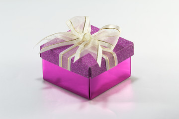 Purple gift box with gold ribbon and bow on white background