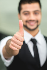 The successful indian businessman show thumb up and look