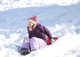 Fototapeta na wymiar young girl plays with sledding on snow in the winter in the moun