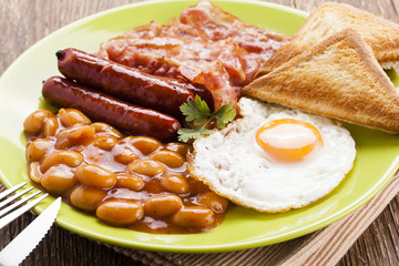 Full english breakfast with bacon, sausage, fried egg, baked bea