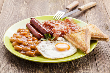 Full english breakfast with bacon, sausage, fried egg, baked bea
