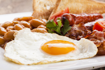 Full english breakfast with bacon, sausage, fried egg, baked bea
