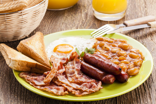 Full english breakfast with bacon, sausage, fried egg, baked bea