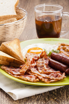 Full english breakfast with bacon, sausage, fried egg, baked bea