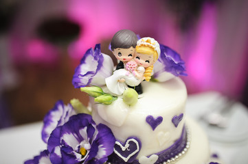 Wedding cake decorated with beautiful violet flowers.