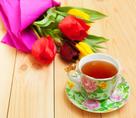 Fototapeta na wymiar cup of tea with bouquet on wooden table