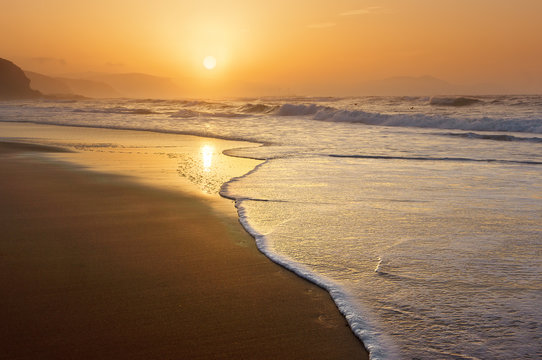 Fototapeta beach at sunset with wave foam