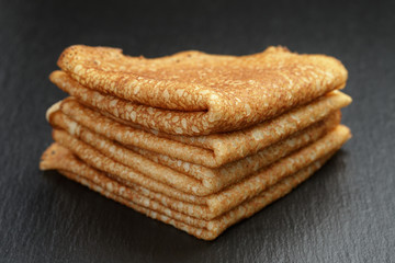 thin crepes or blinis folded in triangles on slate board