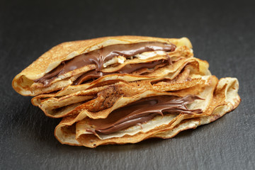 thin crepes or blinis with chocolate cream on slate board