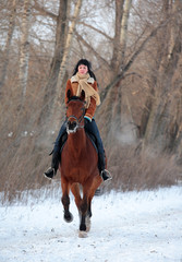 Woman galloping horseback on winter road