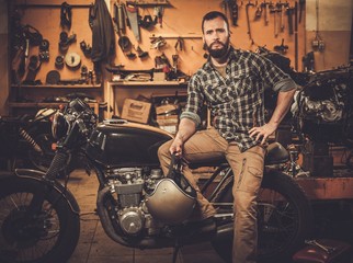 Mechanic with cafe-racer motorcycle  in custom garage