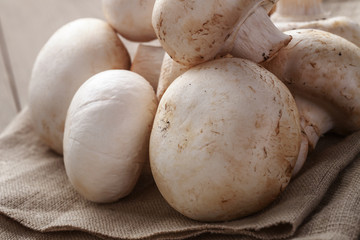 heap of fresh white mushrooms on sack cloth over table