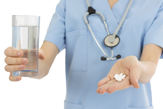 Nurse giving tablets with a glass of water