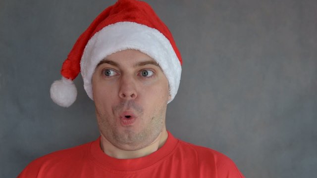 Young man in red santa hat  - surprised face.