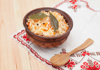 sauerkraut in ceramic bowl with wooden spoon on wooden table wit