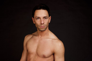 Fototapeta premium Young attractive guy without a shirt. Handsome naked man posing in studio. Atelt. Fitness and healthy lifestyle.