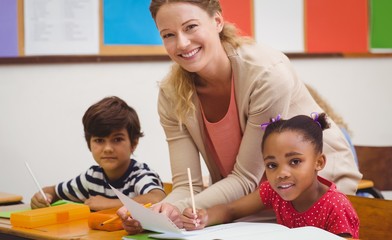 Pretty teacher helping pupil in classroom