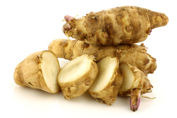 topinambur roots and a cut one on a white background