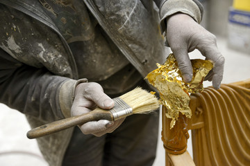 Carpenter Applying Golden Leaf To A Furniture