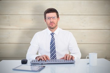 Composite image of businessman working at his desk