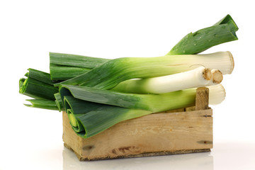 freshly  harvested leek in a wooden box on a white background
