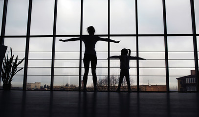 Fototapeta na wymiar Silhouette of mother and daughter in the gym