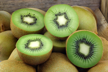 green kiwi fruit and some cut ones in a wooden box