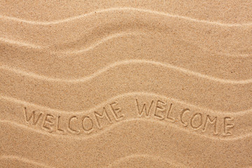 Welcome inscription on the wavy sand