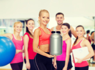 smiling sporty woman with jar of protein
